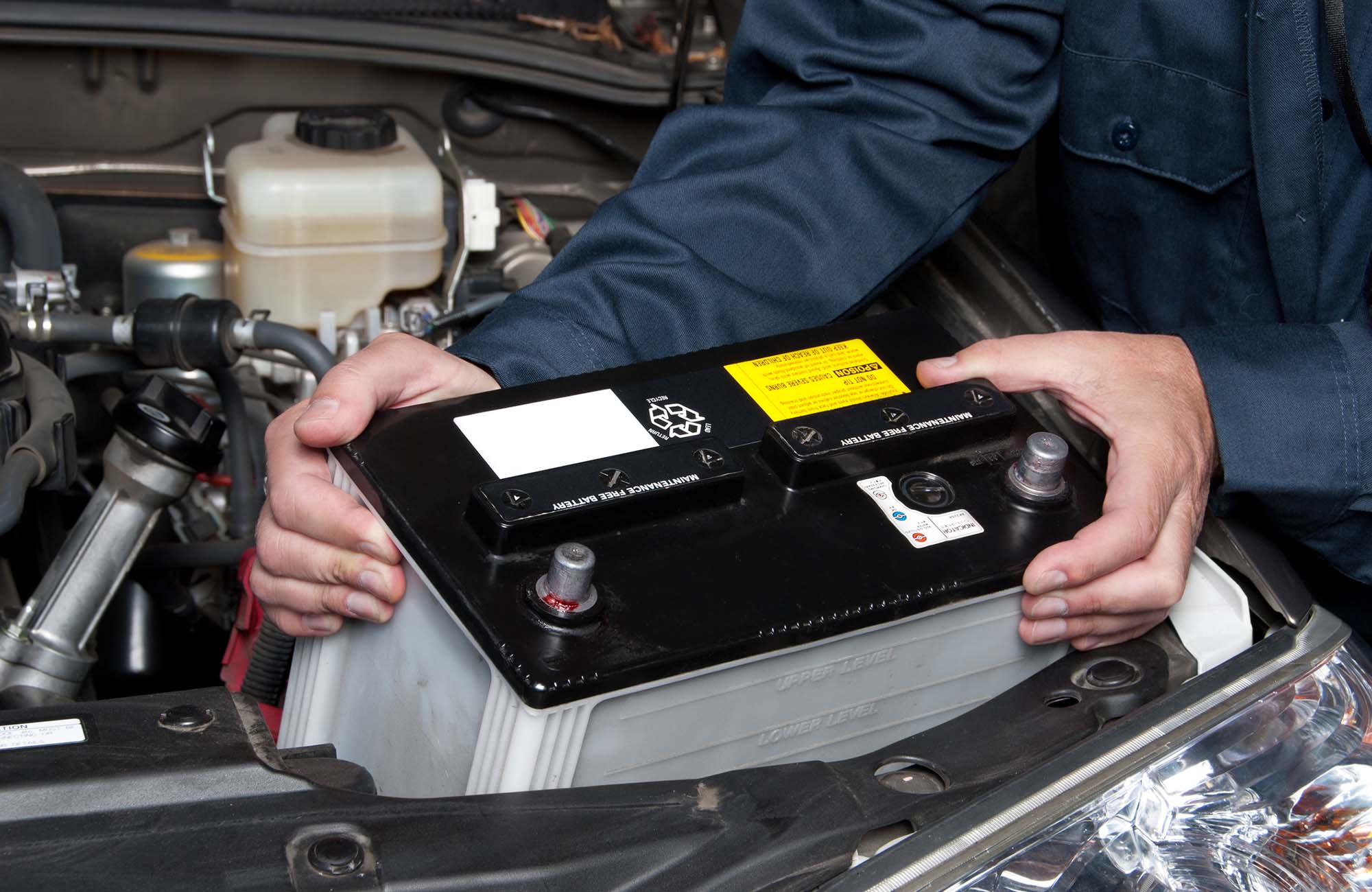 Auto mechanic replacing car battery. A car mechanic replaces a battery.