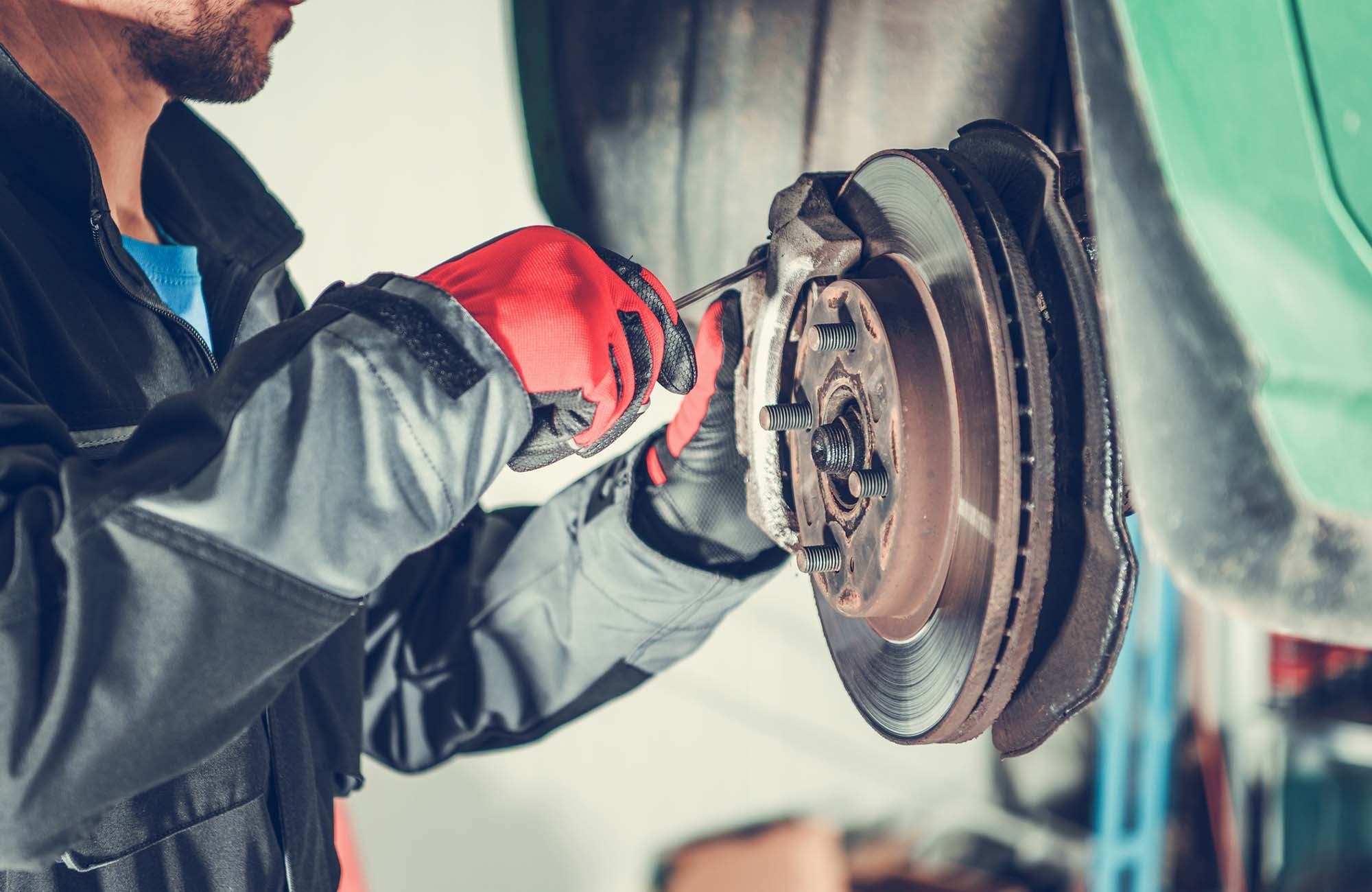 Car Brakes Replacing. Car Brakes Servicing by Caucasian Vehicle Mechanic in His 30s. Automotive Industry
