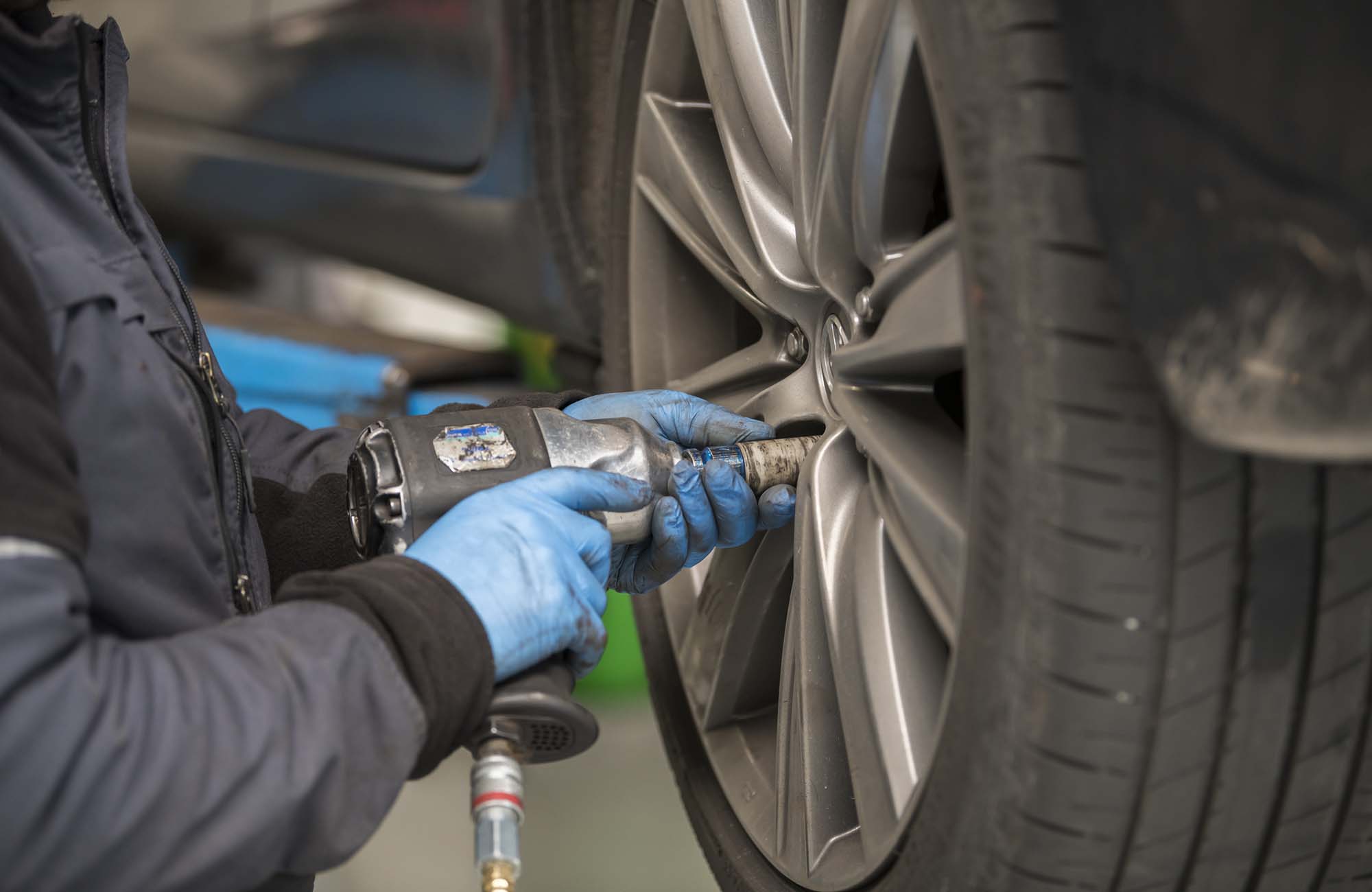 Changing winter tyres for summer tyres. car mechanic is tightening bolts on a wheel. automotive industry. Close-up of a wheel. car service, repair, maintenance concept. Garage workshop.