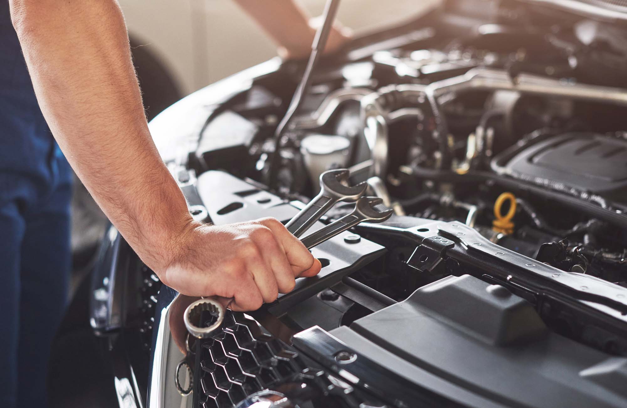 Picture showing muscular car service worker repairing vehicle.
